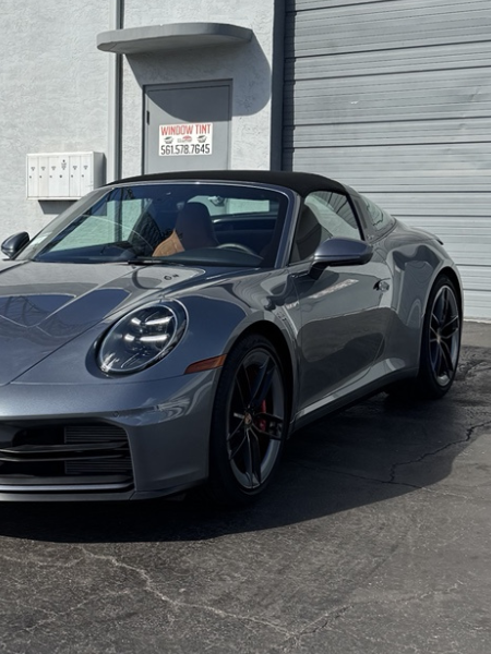 Gray Porsche 911 parked outside a building in sunlight