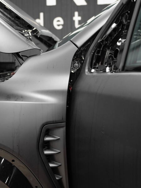 Close-up of two silver car panels with a visible door seam and vent detail in a showroom-like setting