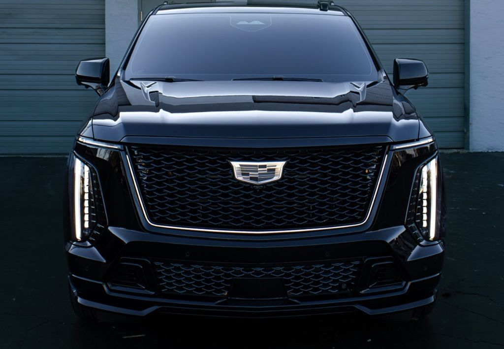 Black Cadillac SUV parked in front of a building with two gray garage doors