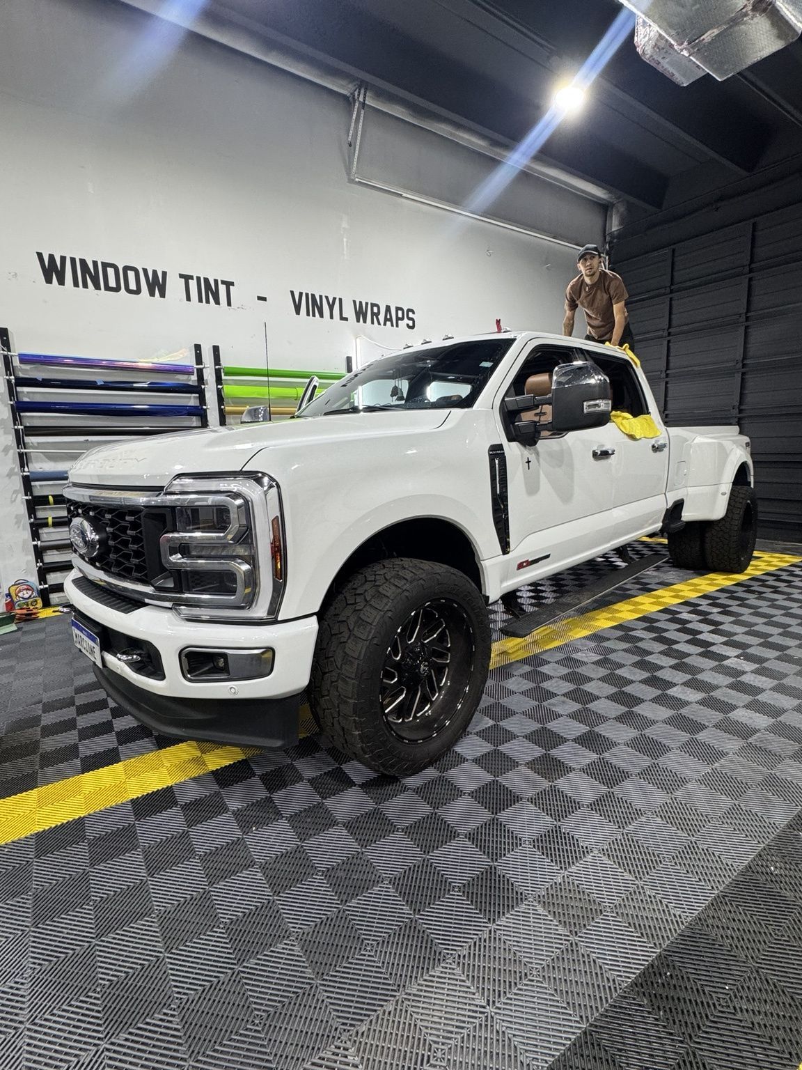 Hand washing a white car window with soap suds during a car wash