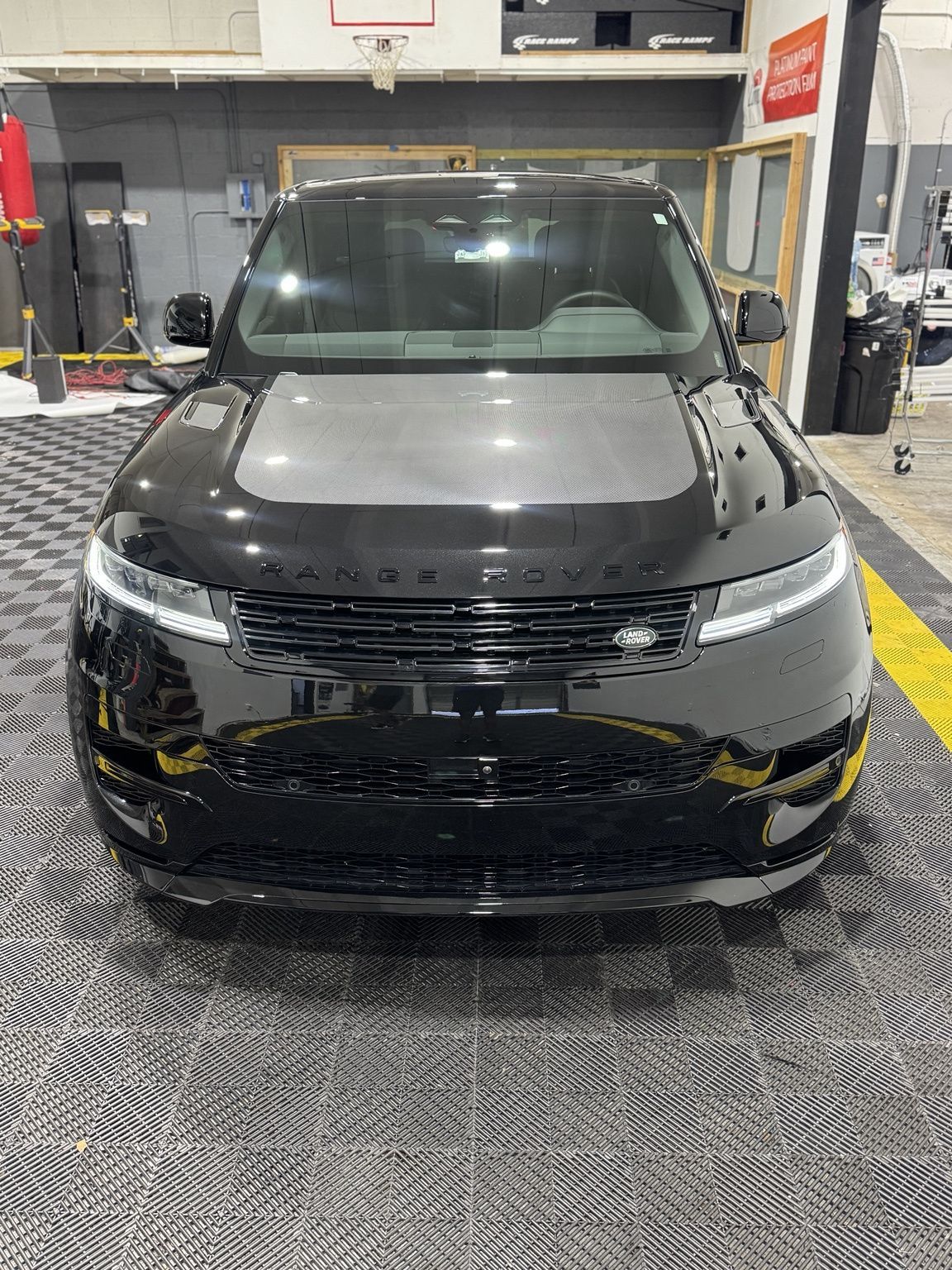Gloved hand polishing a glossy carbon-fiber car surface in a garage
