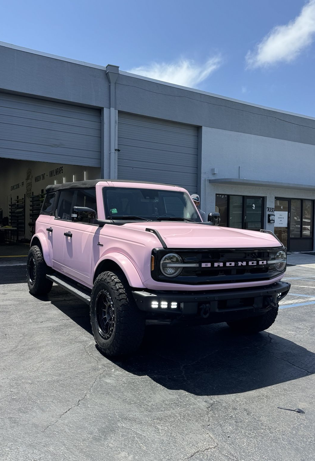 Pink off-road SUV parked outside a commercial building on a sunny day
