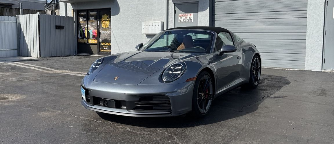 Gray sports car parked outside a garage on a sunny day