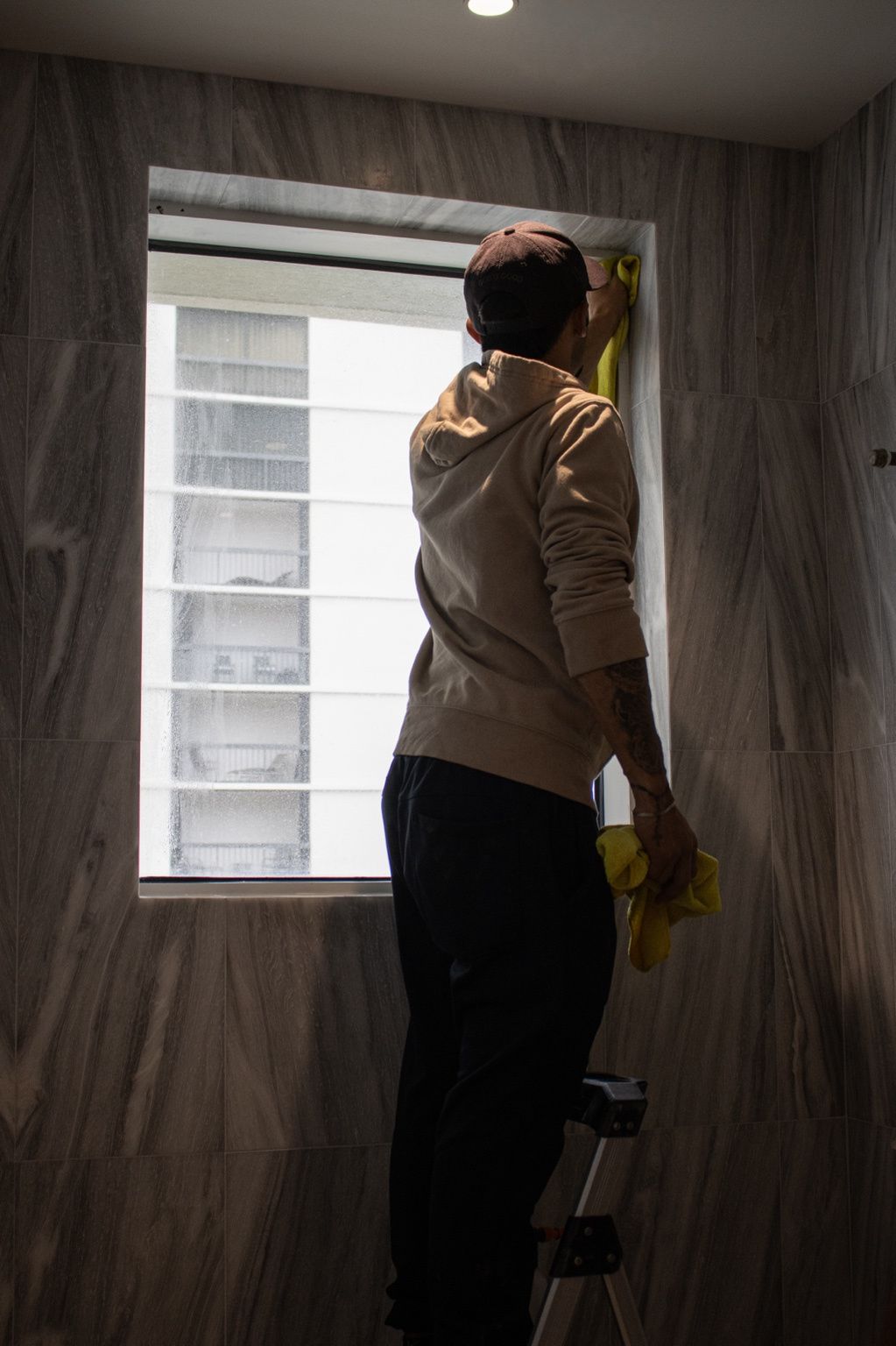 Person cleaning a window with a squeegee in a beige room