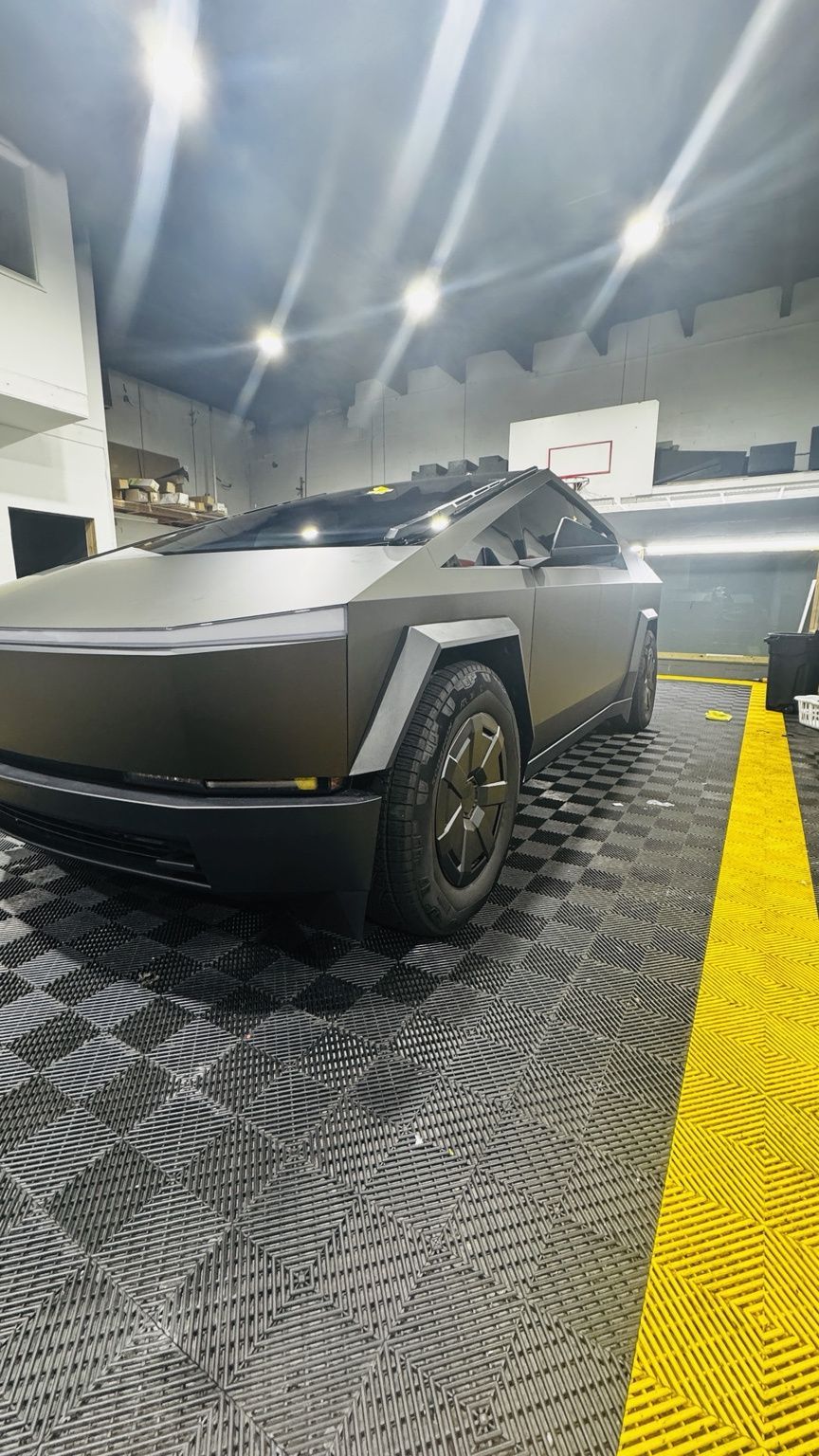 Hand peeling black vinyl wrap from a silver car door