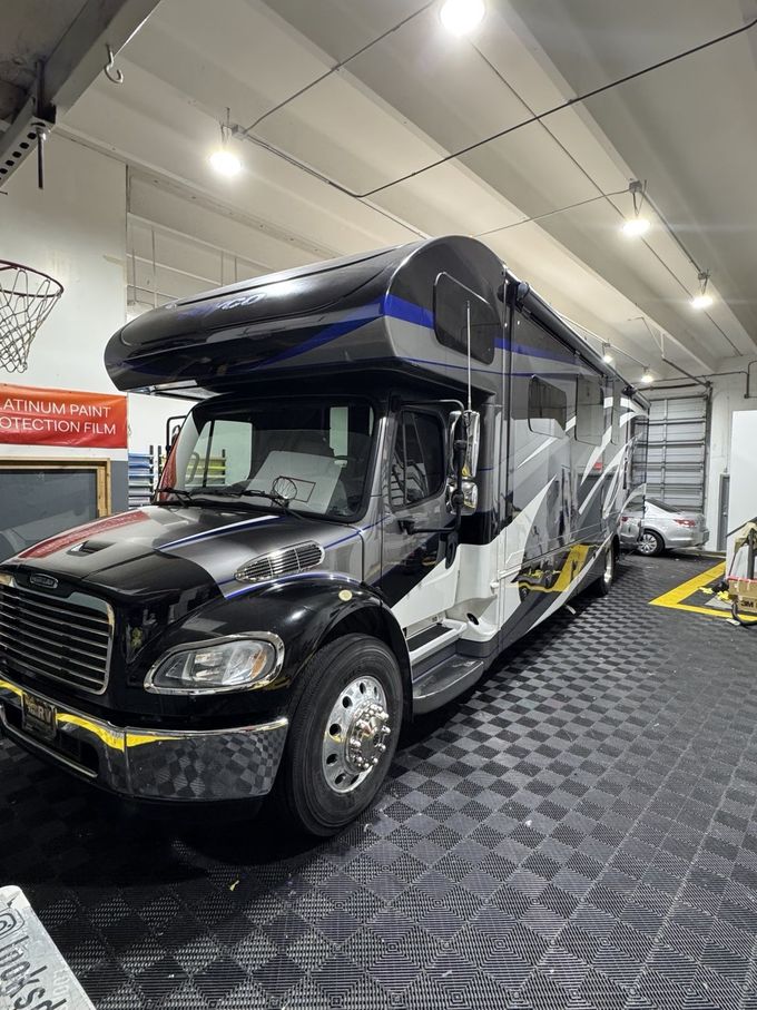 Black and white shuttle bus inside a garage with bright overhead lights.