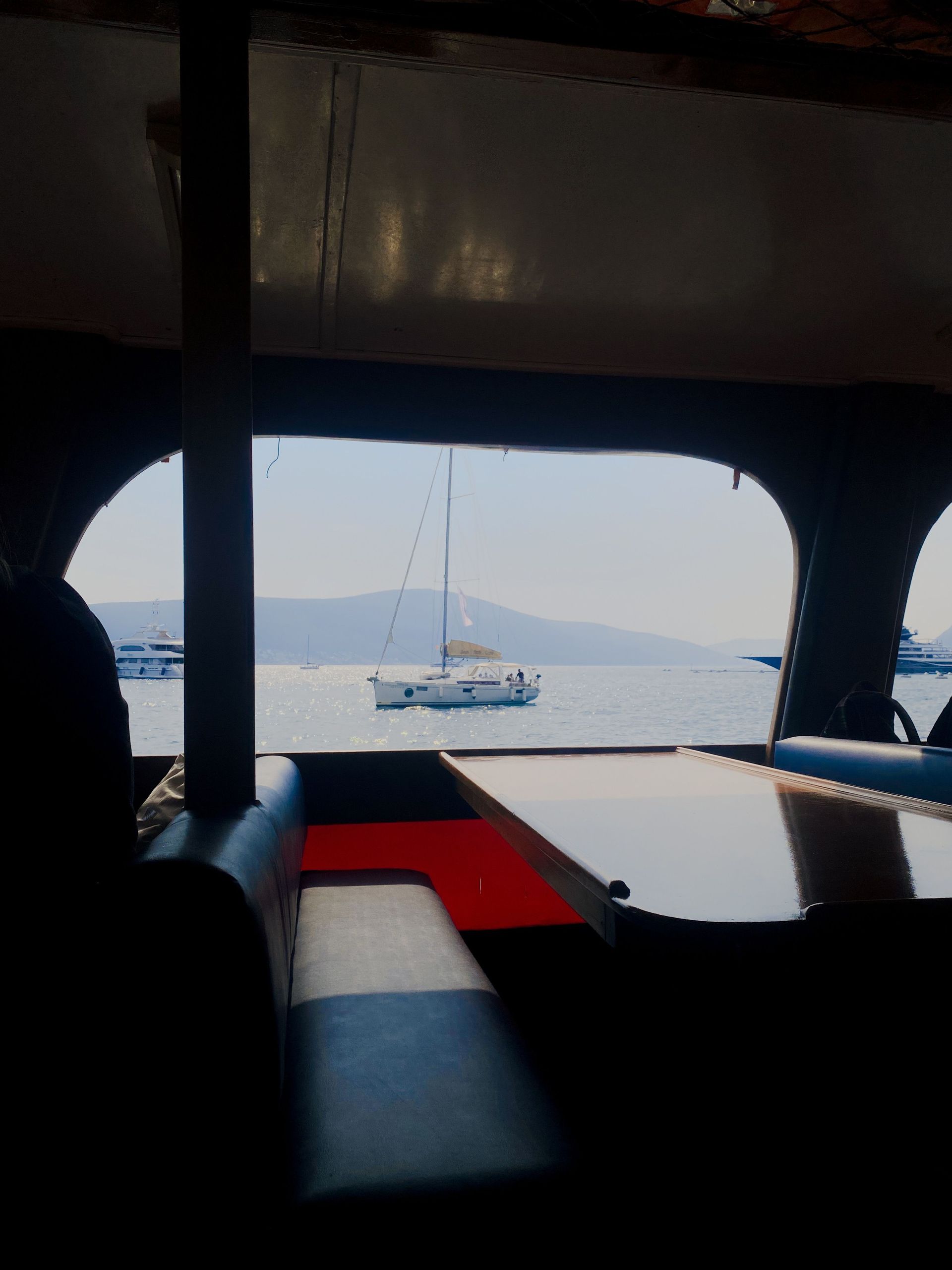 Boat cockpit with wooden steering wheel on calm blue water under a clear sky