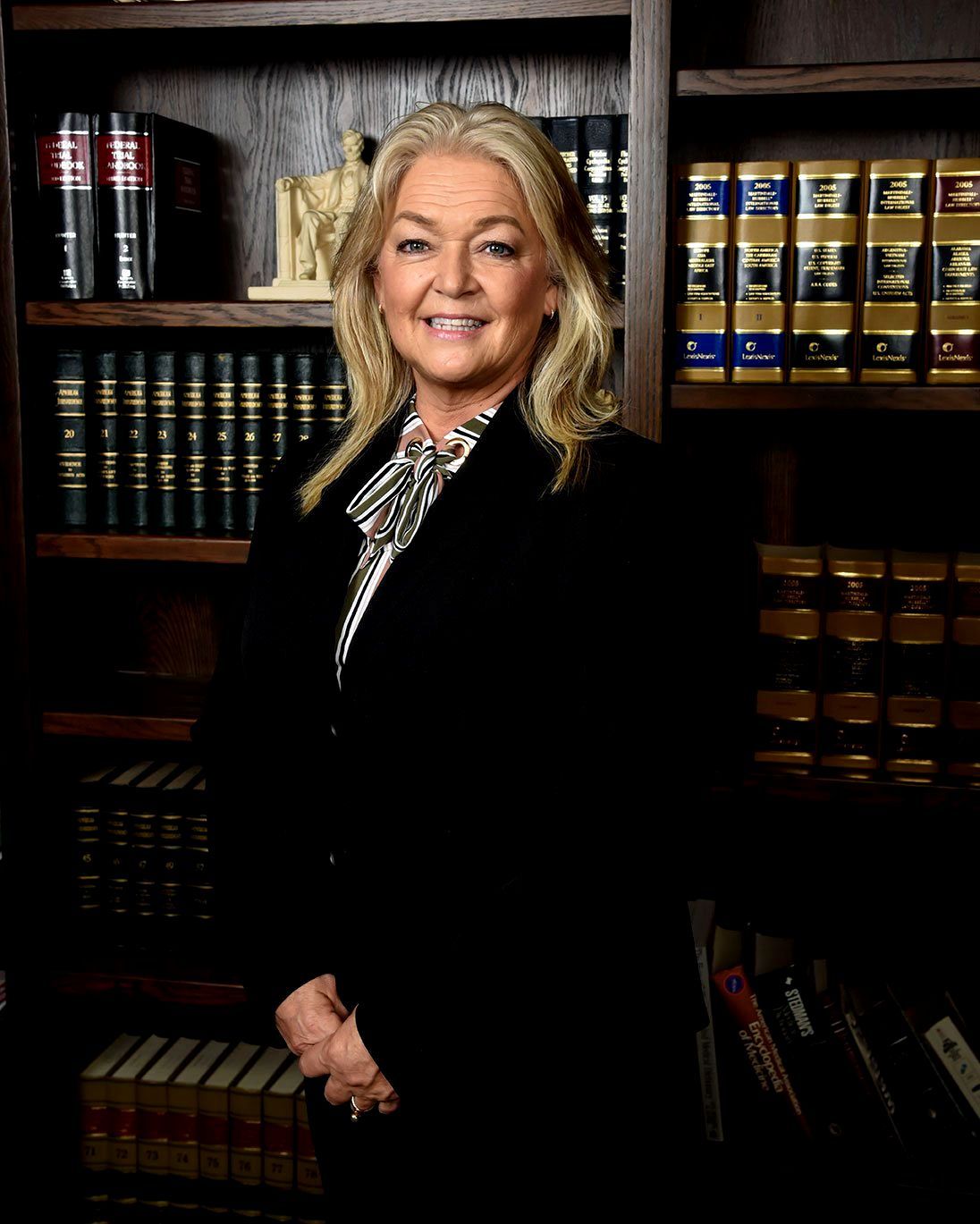 A woman is standing in front of a bookshelf filled with books.