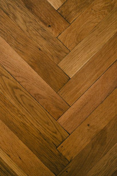 Suelo de madera con diseño de espiga en tonos marrones cálidos.