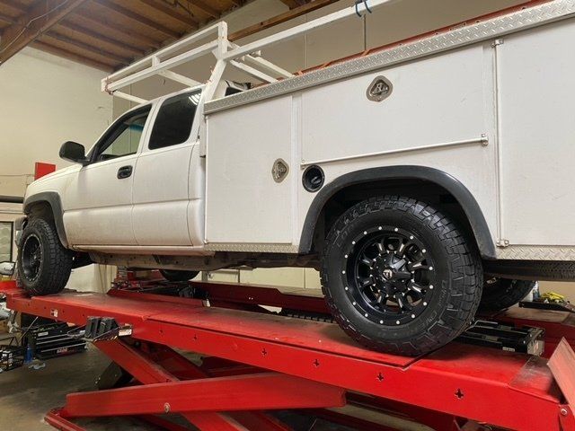 A white truck sitting on top of a red lift - Partner with JCR Performance | Best Auto Repair Shop in Sacramento, CA