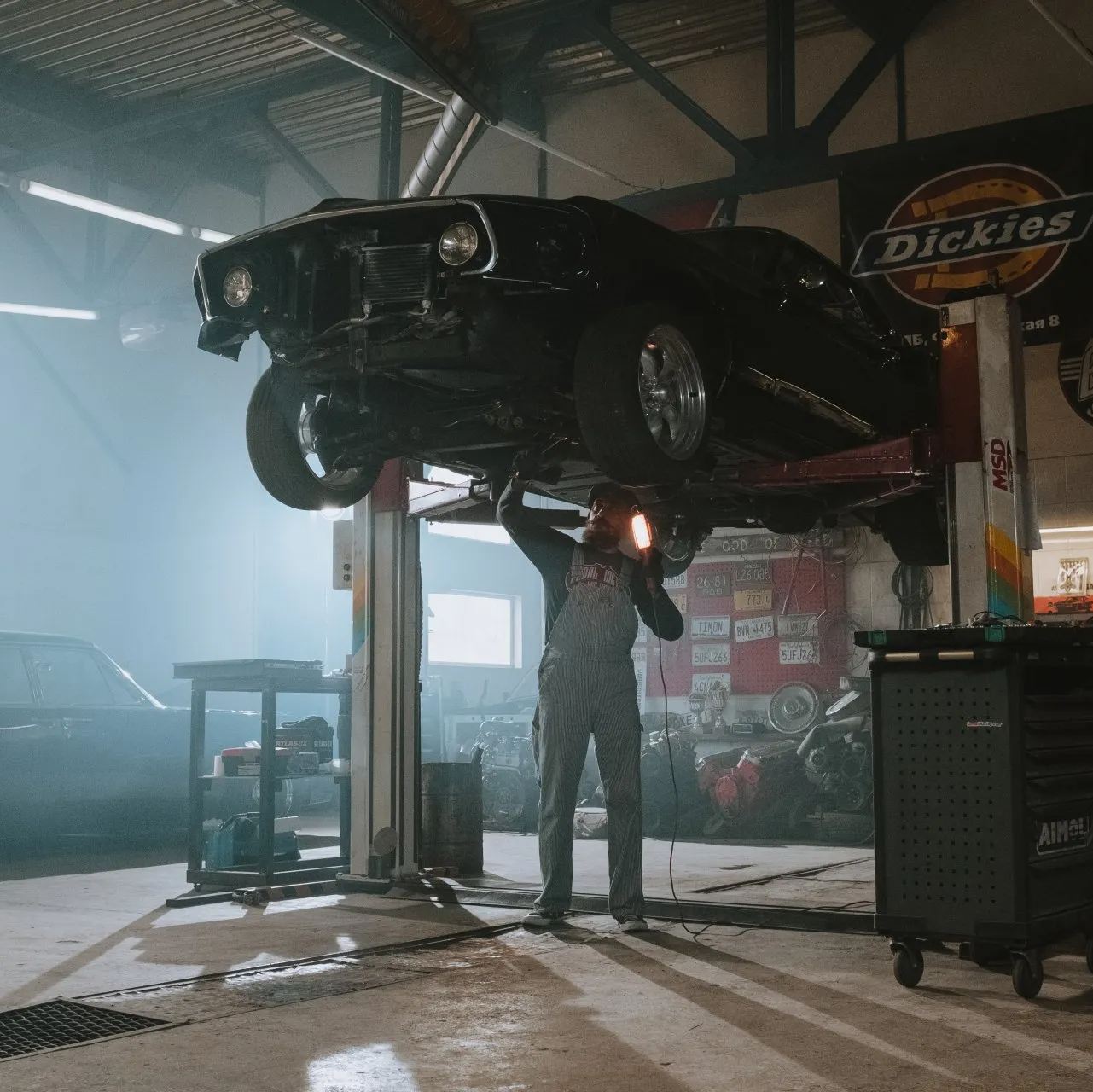 A mechanic working underneath a black car lifted in a garage |JCR Performance Your Trusted Auto Repair Shop in Sacramento, CA