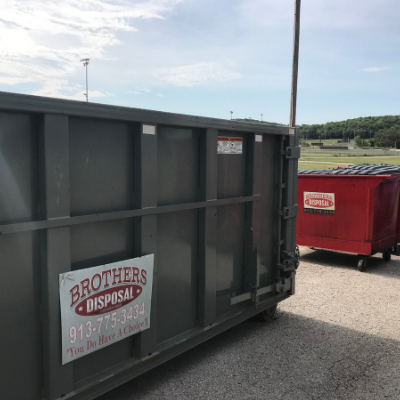A large gray dumpster and a smaller red dumpster labeled 