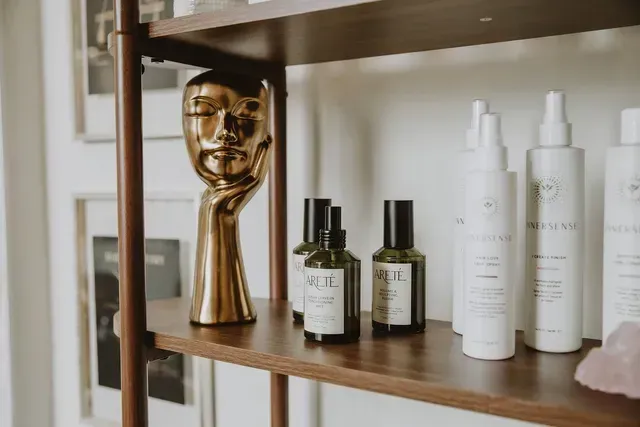 Wooden shelf with skincare bottles and a gold face-shaped decorative sculpture