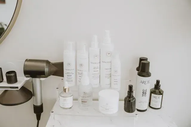 Assorted white and amber skincare bottles and jars arranged on a white bathroom shelf.