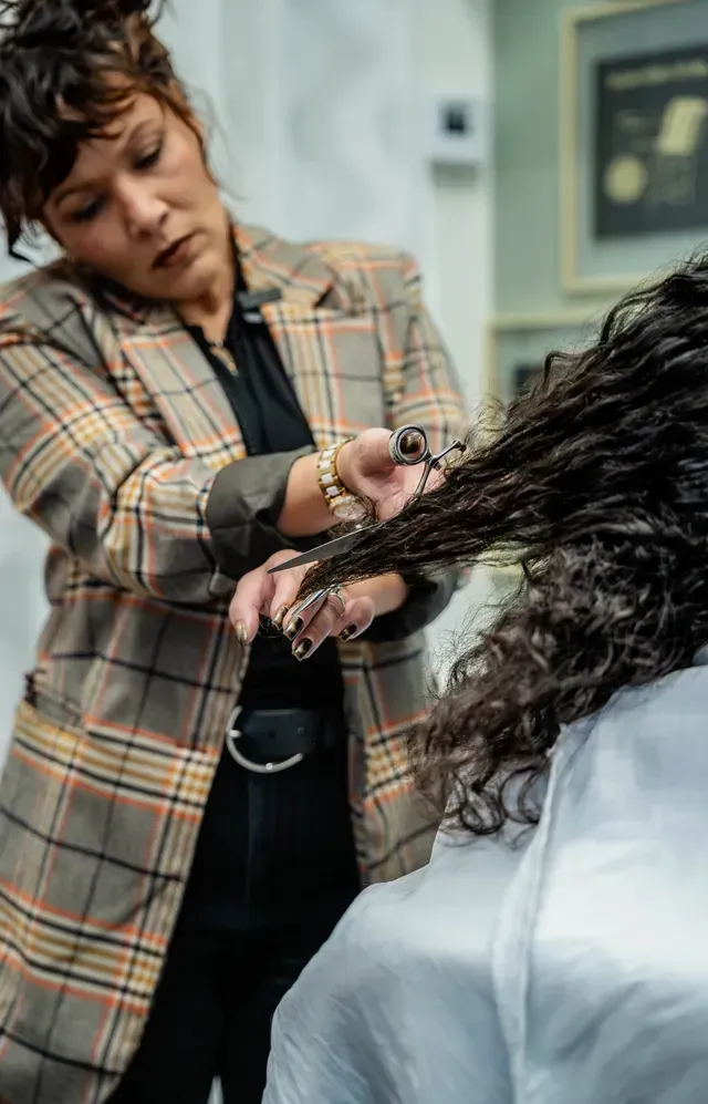 Hairdresser trimming a client’s wet curly hair in a salon