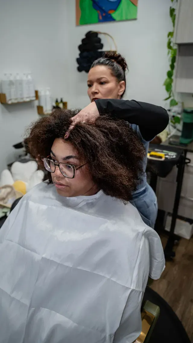 Hairdresser styling a client’s curly hair in a salon chair