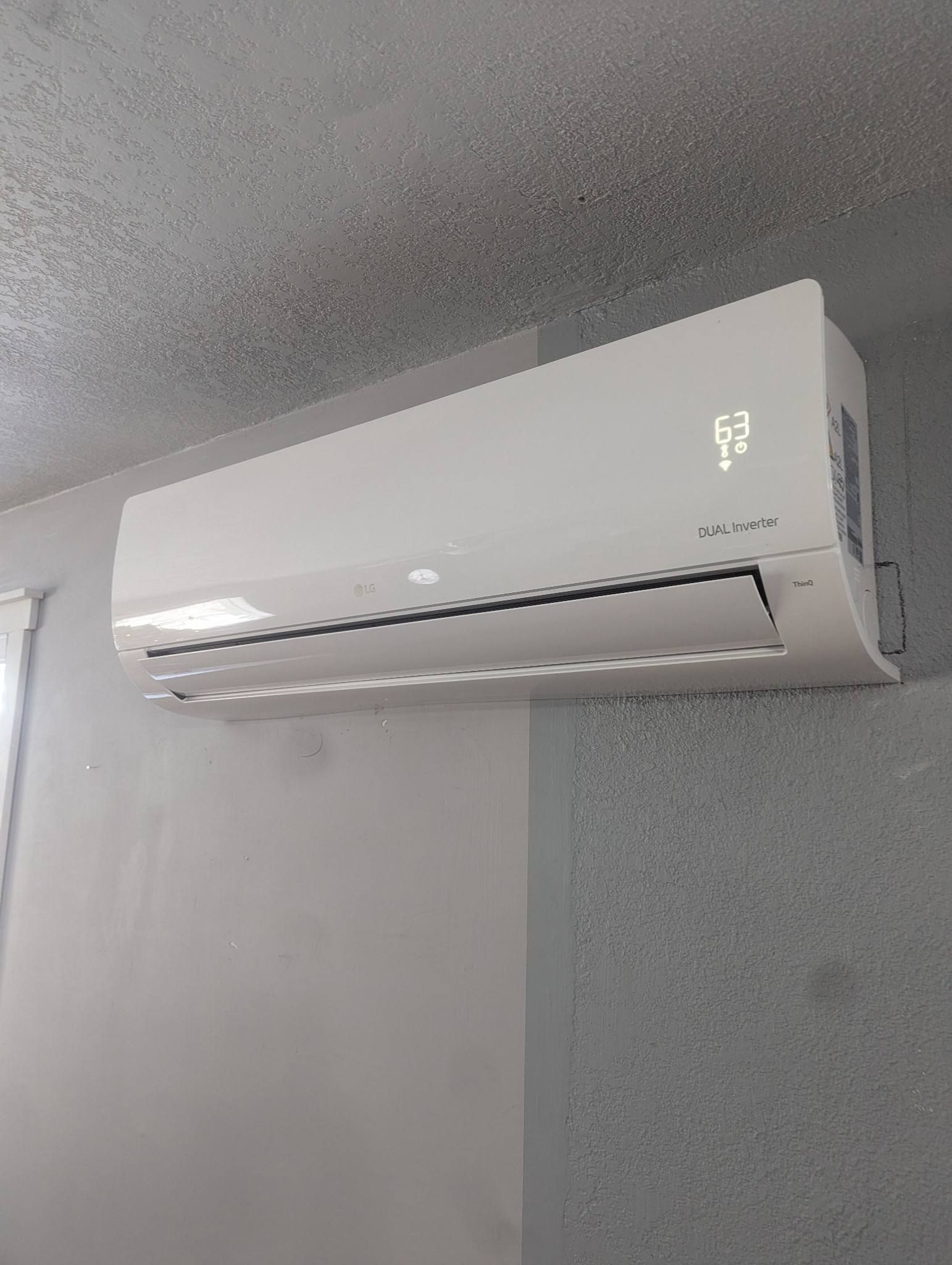 Wall-mounted white air conditioner on a light gray textured wall.