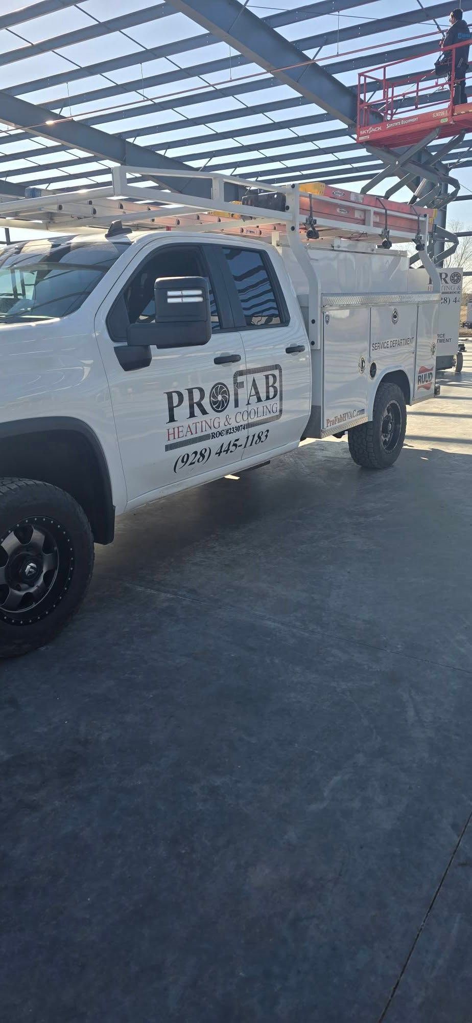 White utility truck parked under a metal canopy in an industrial lot