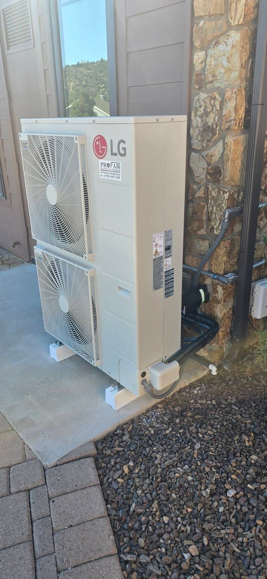 Outdoor LG air conditioning unit beside a house wall on a concrete slab.