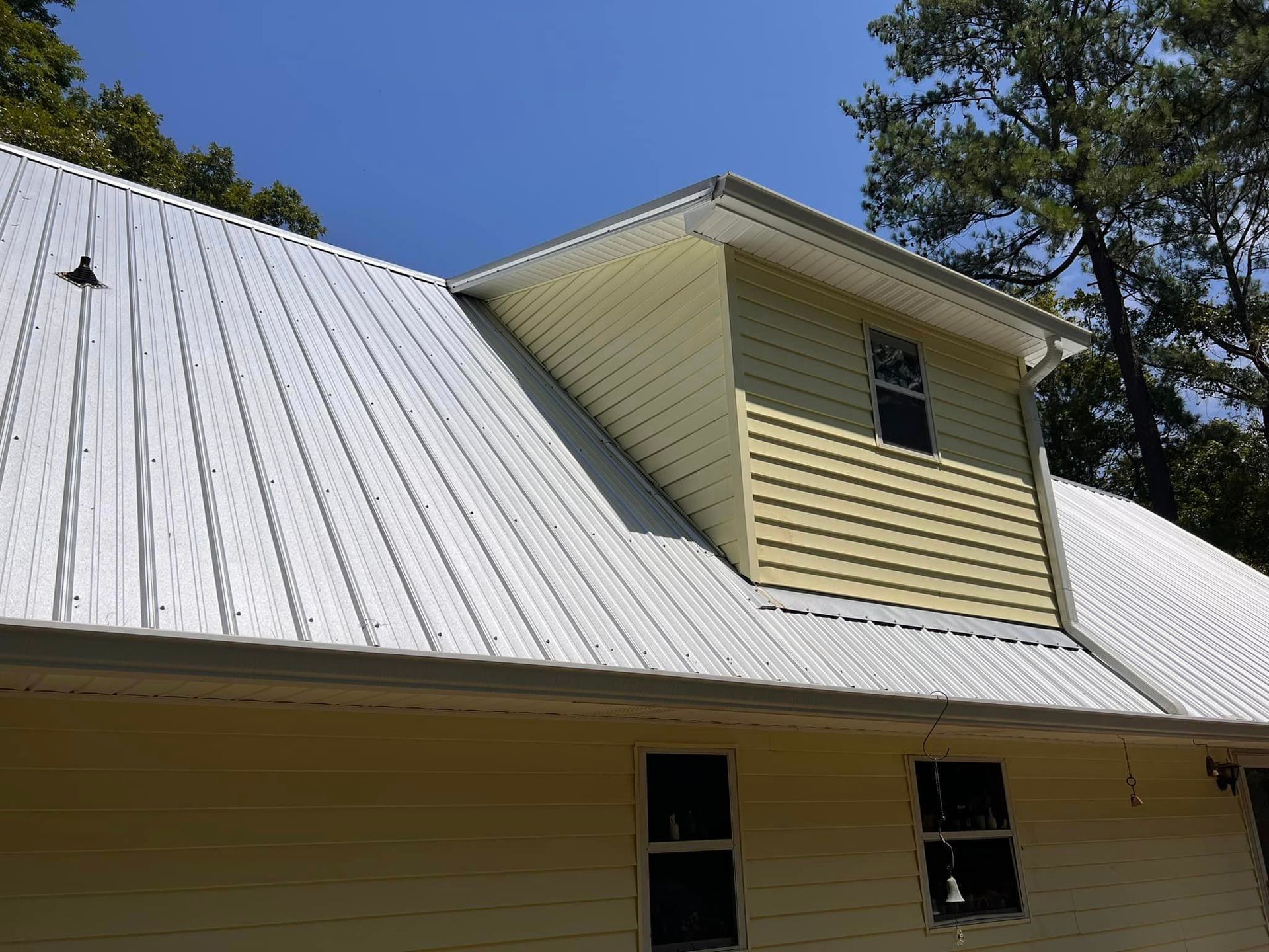 A man is cleaning the roof of a house with a high pressure washer.