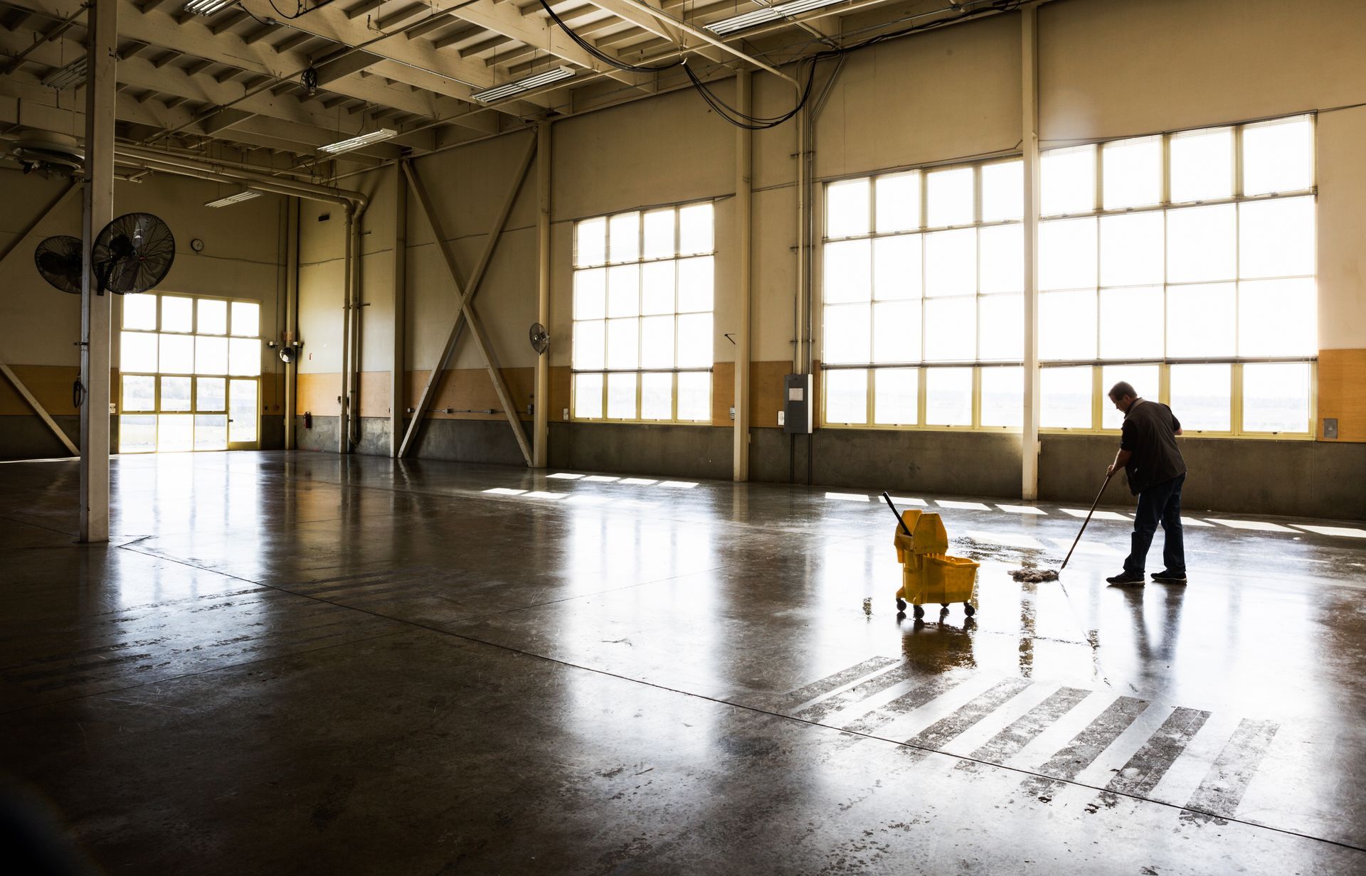 A man is mopping the floor of an empty warehouse A man is mopping the floor of an empty warehouse