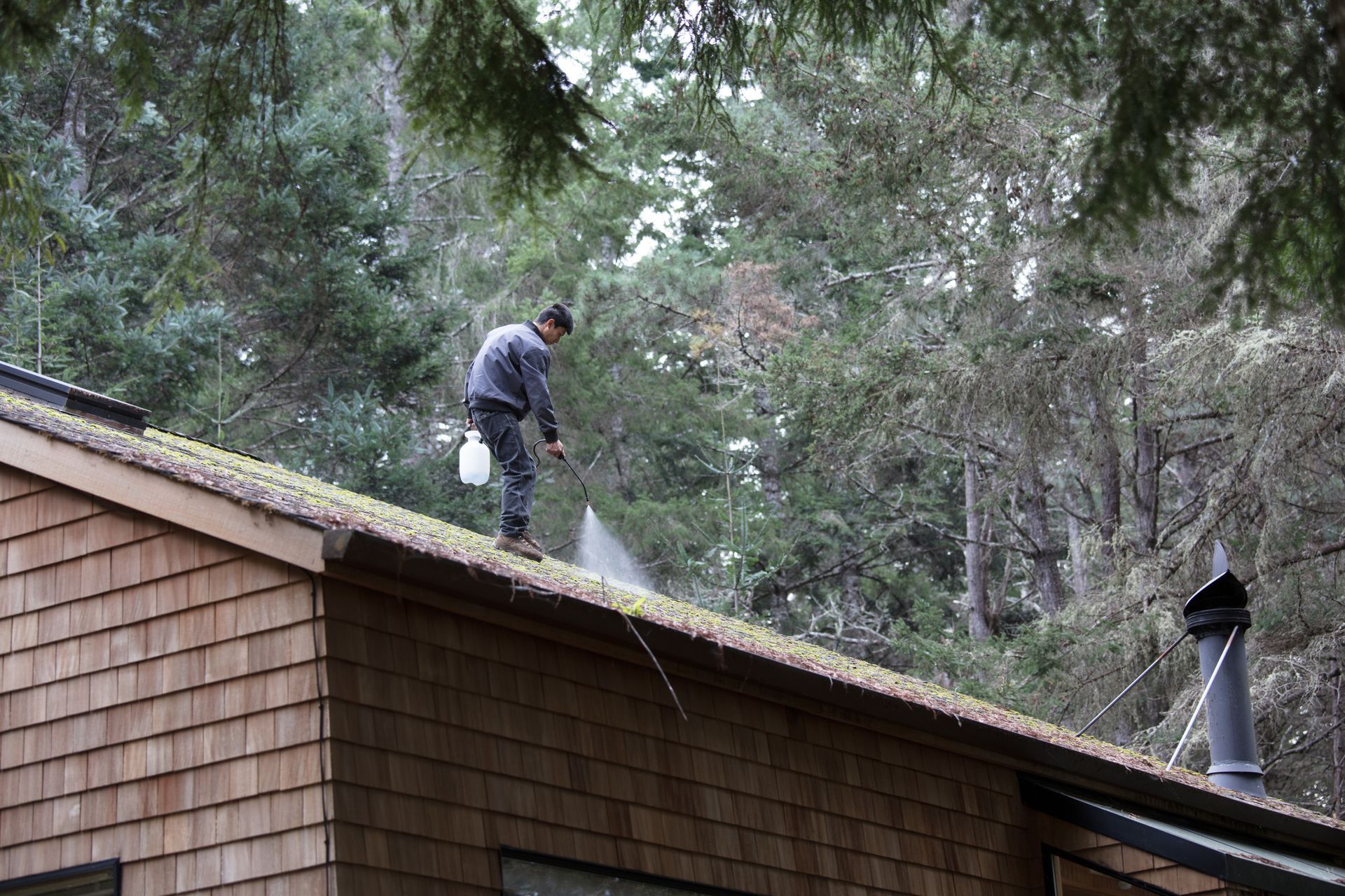 A man is spraying water on the roof of a house A man is spraying water on the roof of a house