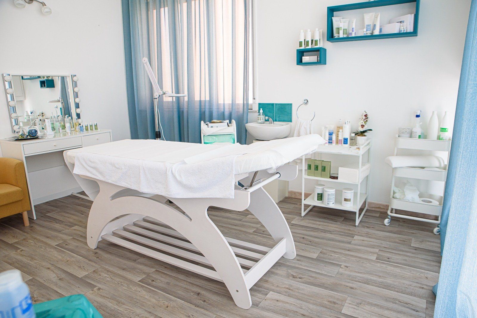 Sala per trattamenti estetici con tavolo bianco, prodotti e dettagli blu.