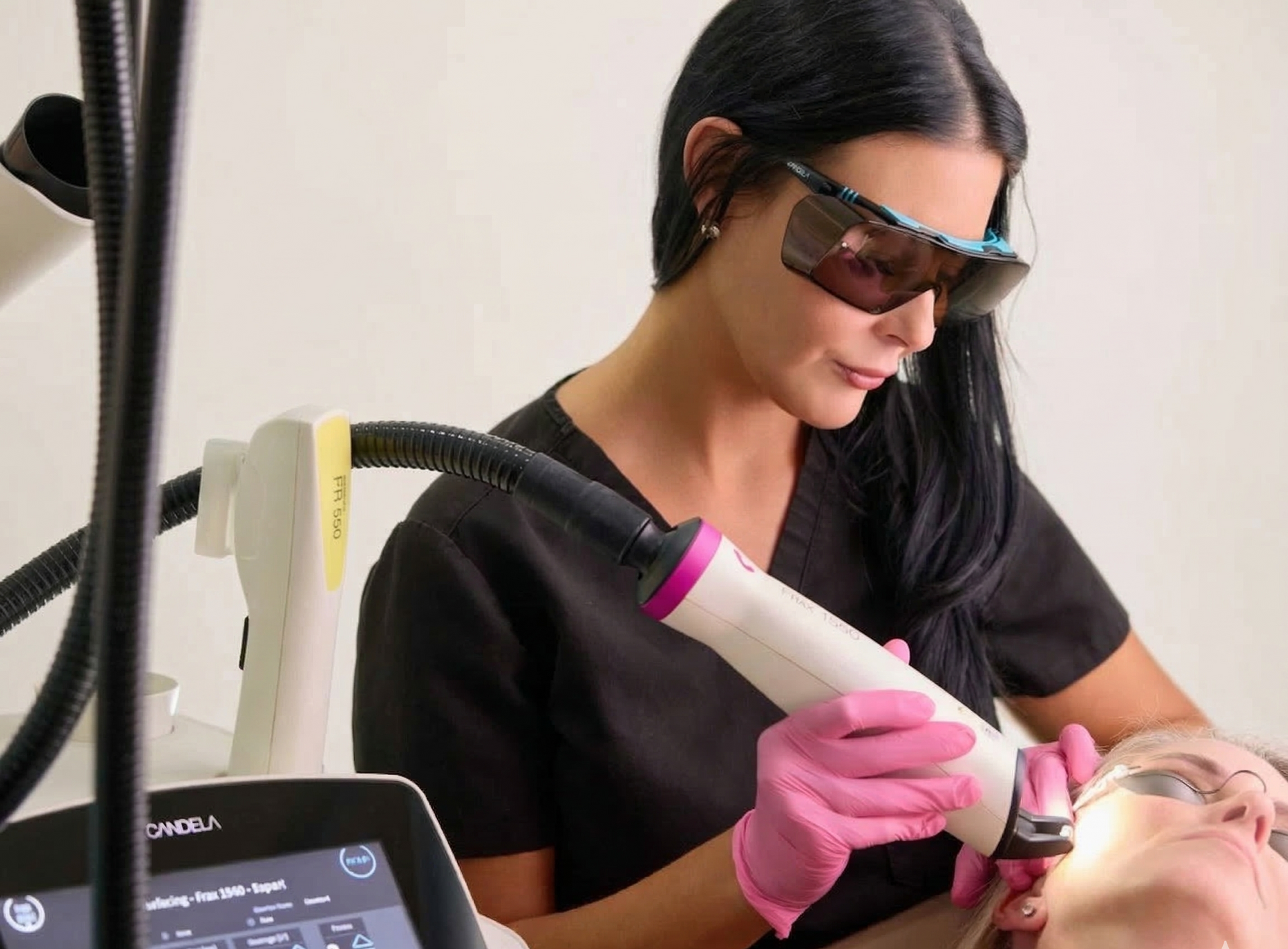 Technician using a handheld laser device on a client's face during a skincare treatment