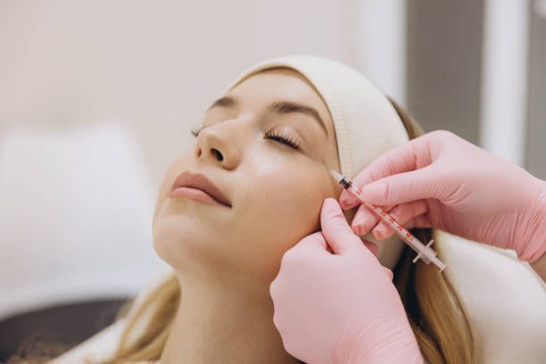 Gloved hands adjusting a woman's ear with a small tool in a clinic setting