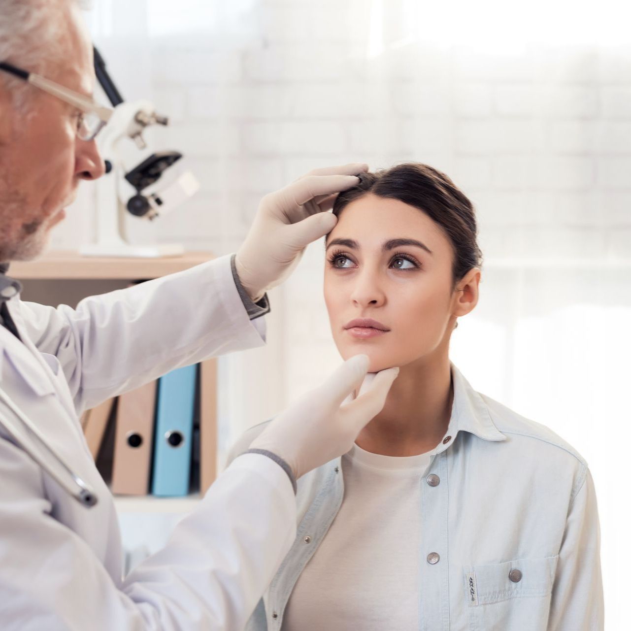 Doctor examining a patient's face in an office setting.
