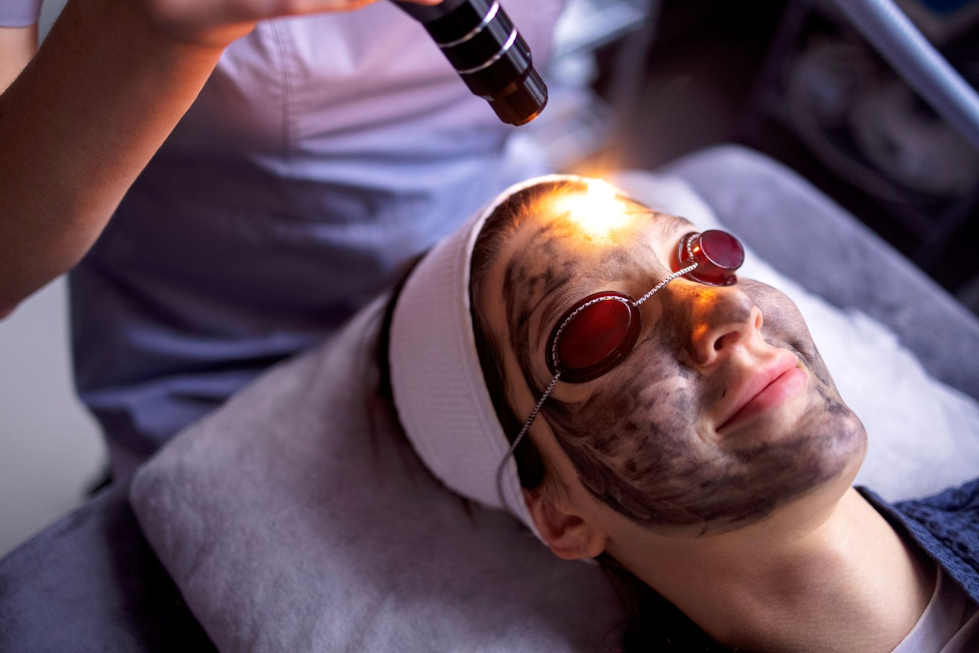 Woman receiving facial microdermabrasion treatment; setting is a spa, close-up.