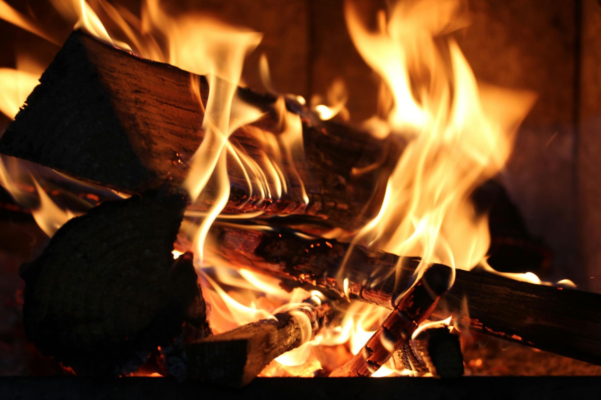 Burning logs in a fireplace, flames are orange and yellow.