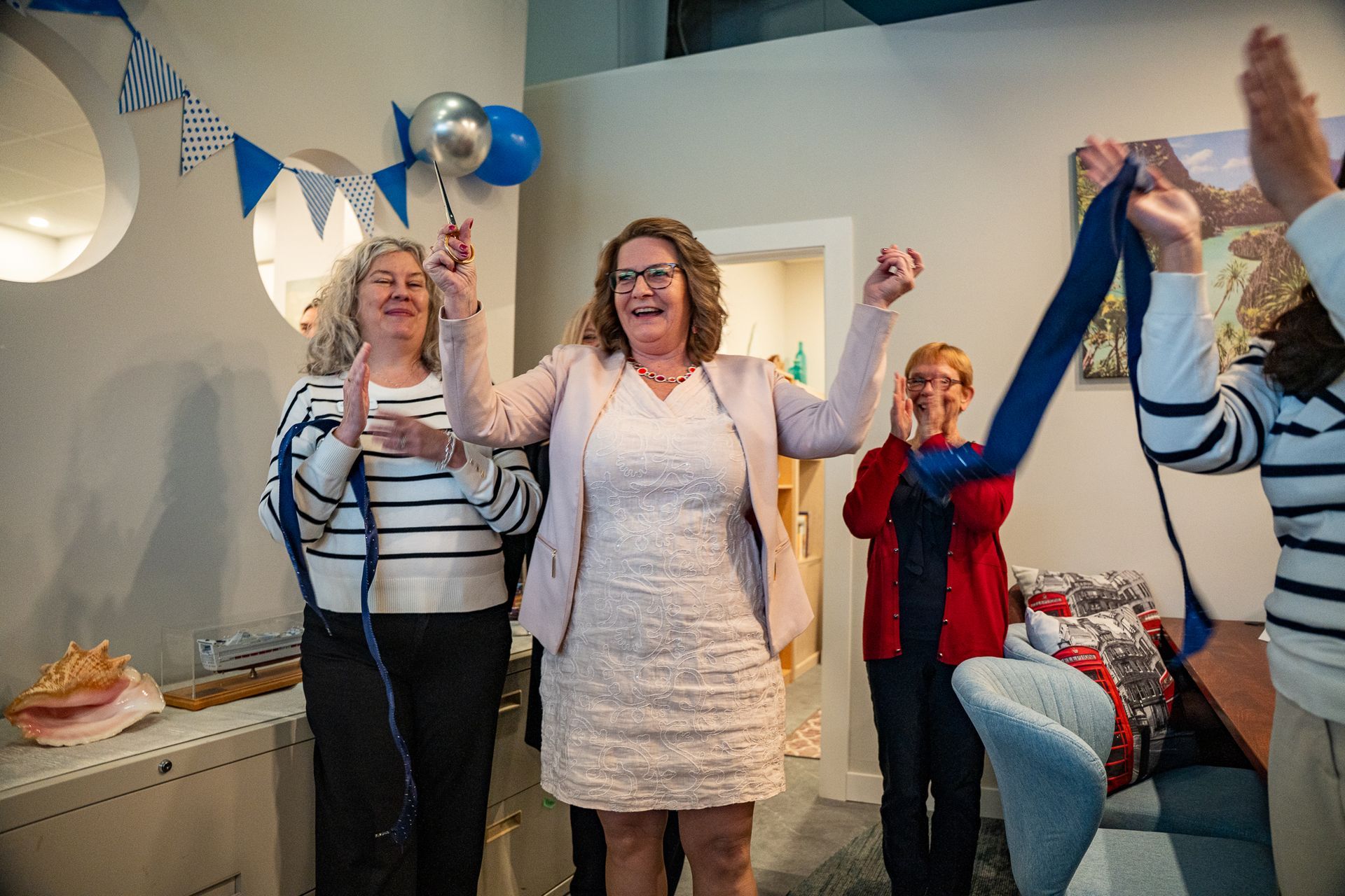 People celebrating in a living room, raising arms and balloons during a party