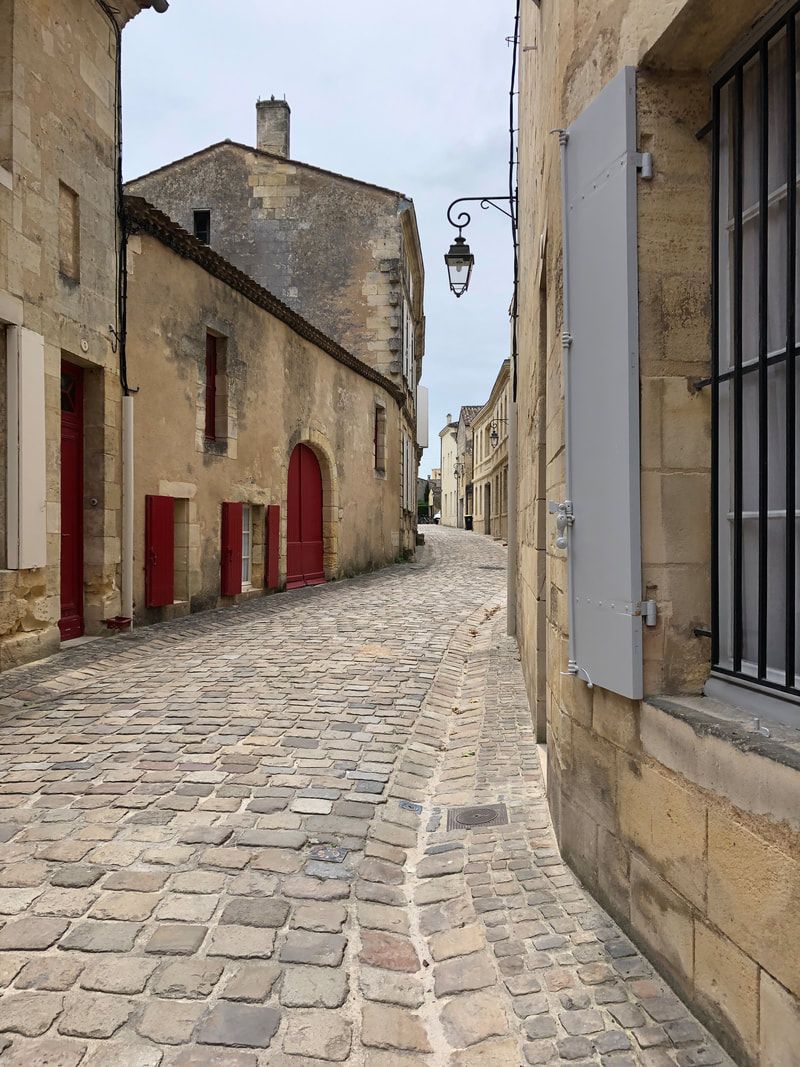 french village A cobblestone street between two buildings with red doors.