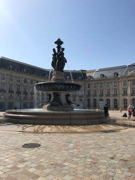 place de la bourse A large fountain in the middle of a square in front of a building.