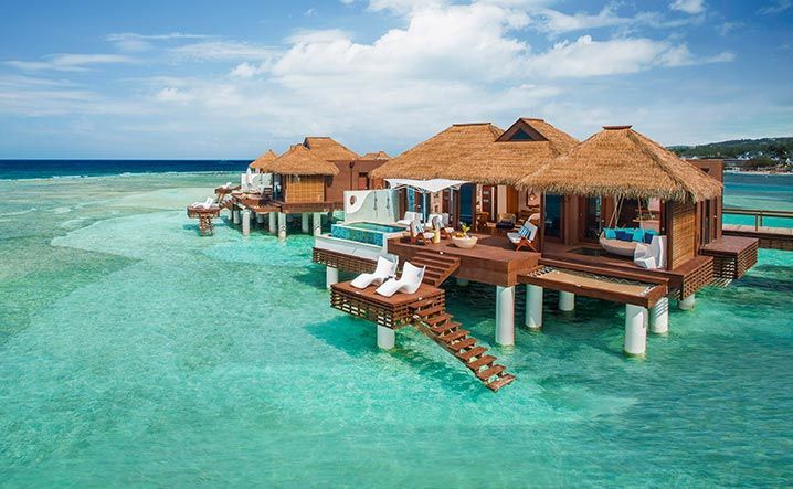 stilt villas A group of thatched huts on stilts in the middle of the ocean.