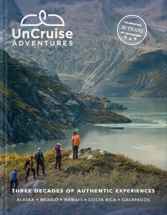 Hikers on a mountain overlook above a fjord, with UnCruise Adventures logo and trip text overlaid.