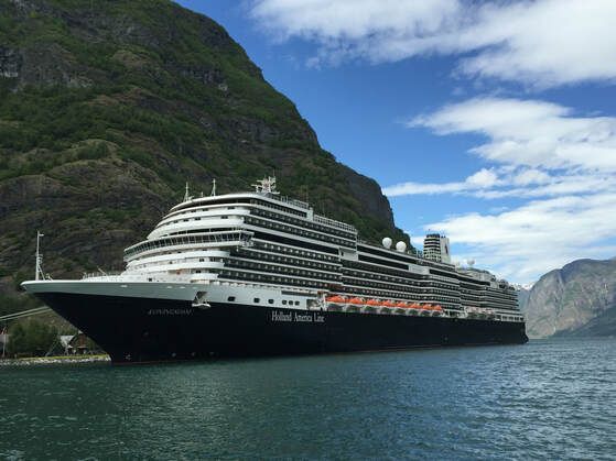 cruise ship with mountain backdrop A large cruise ship is docked in the water near a mountain.