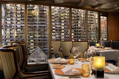 dining room A restaurant with tables and chairs and a wall of wine bottles.