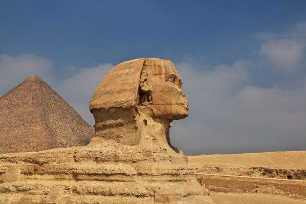 picture of a Egyptian statue A statue of a sphinx with a pyramid in the background.