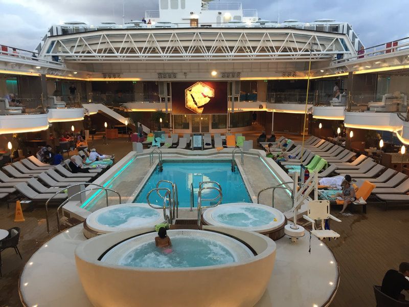 pool deck cruise ship A large cruise ship with a large swimming pool and hot tubs.