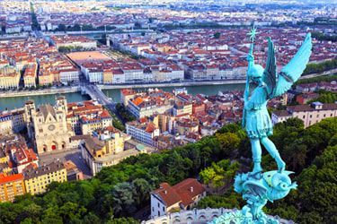 statue of an angel An aerial view of a city with a statue of an angel in the foreground.