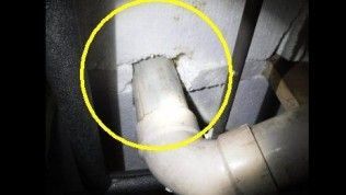 A white pipe penetrating a wall of white insulation material, highlighted by a yellow circle.