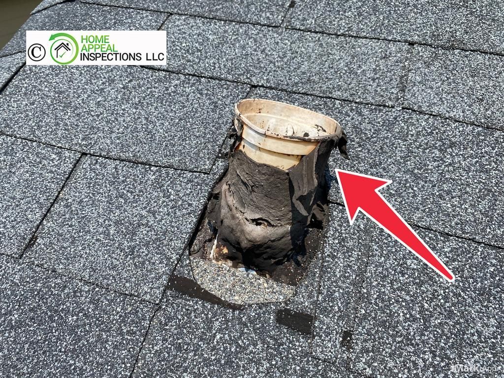 A damaged, weathered plumbing vent boot on an asphalt shingle roof, with a red arrow pointing to the degraded seal.
