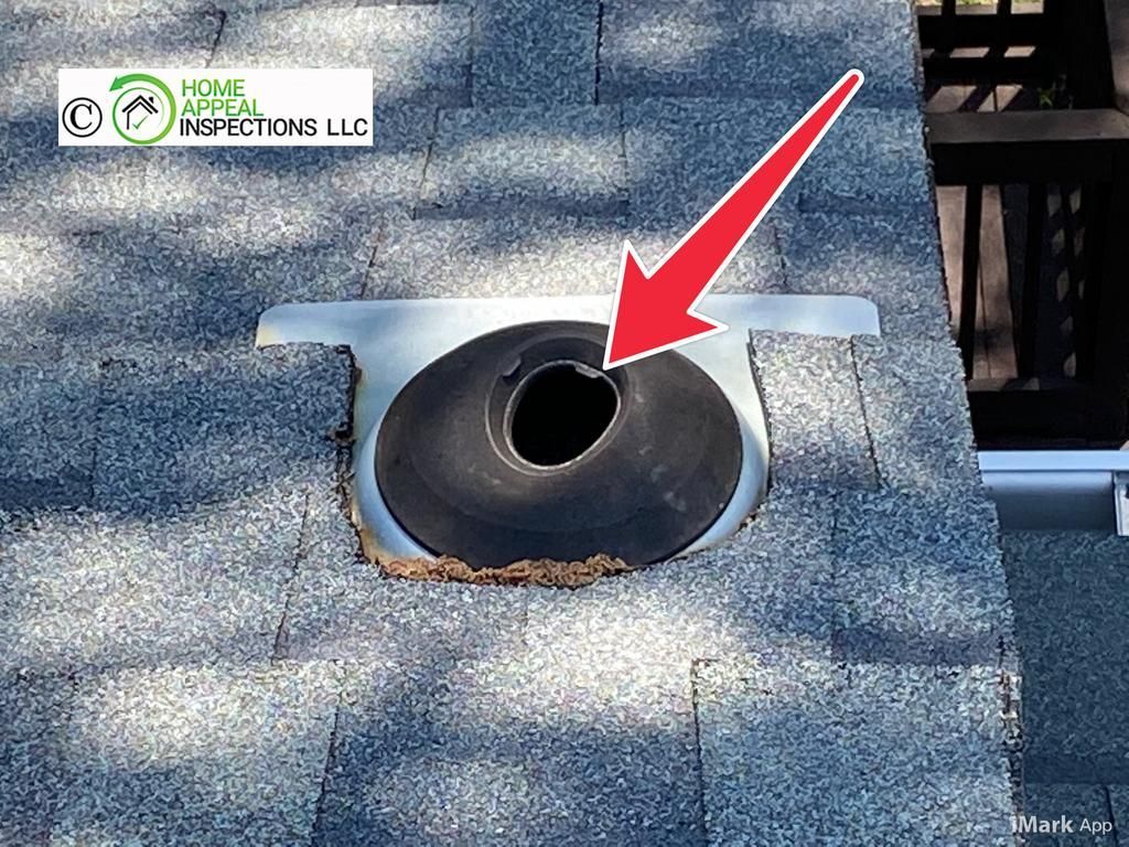 A roof vent boot with a cracked rubber collar, highlighted by a red arrow on an asphalt shingled roof.
