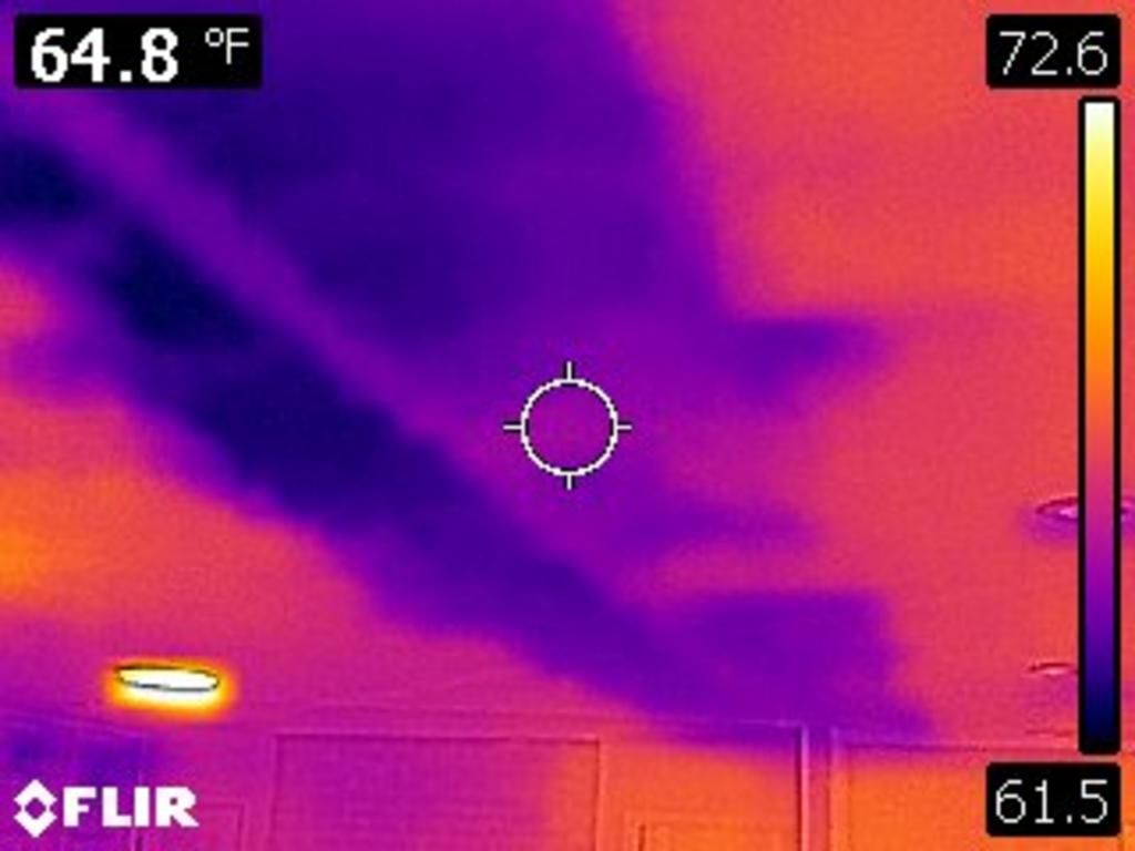 Thermal image of a ceiling showing cool, dark purple areas indicating moisture or air leaks against a warmer orange background.