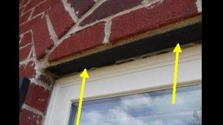 Two yellow arrows point to a gap between a red brick wall and the top of a white window frame.