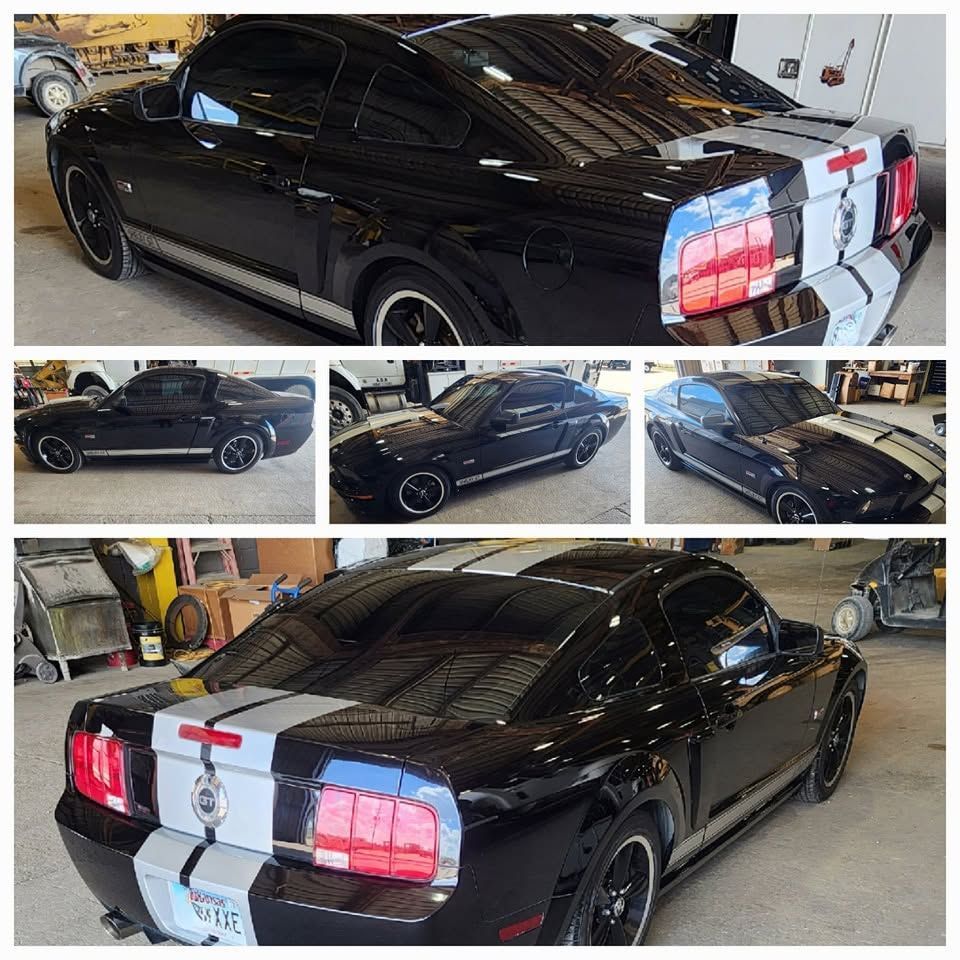 Black Ford Mustang coupe with white racing stripes, shown in a garage from multiple angles.