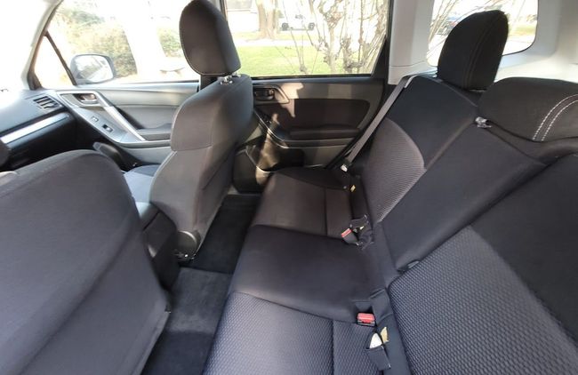 Rear seats and front cabin of a car, with black upholstery and folded center armrest.