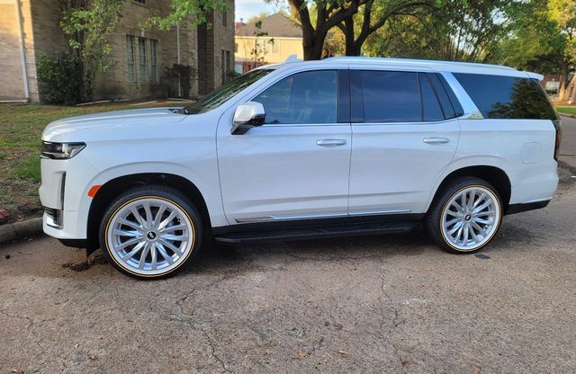White SUV parked on a gravel driveway beside a brick house and trees.